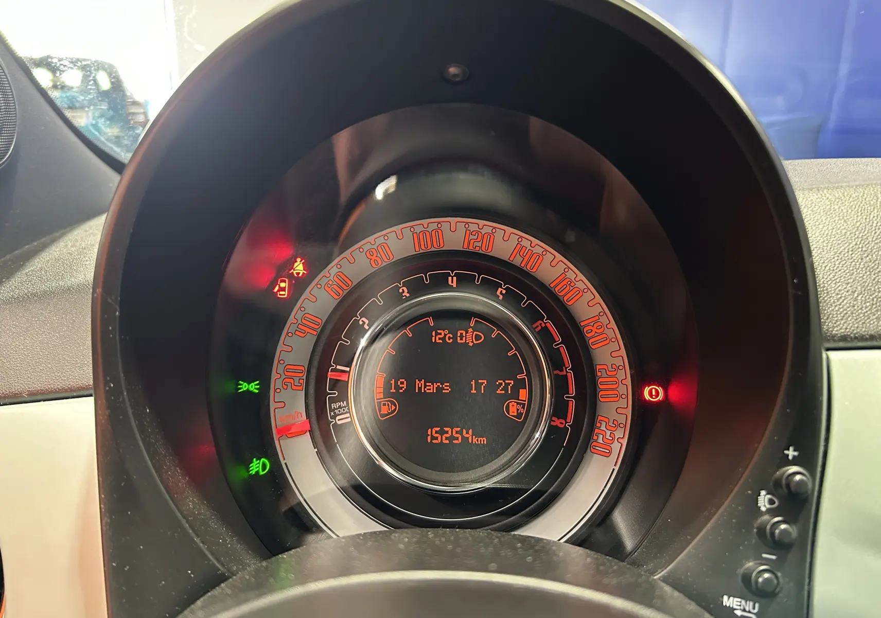 Vue rapprochée du tableau de bord de la Fiat 500 2023, affichage numérique orange avec compteur et témoins lumineux.