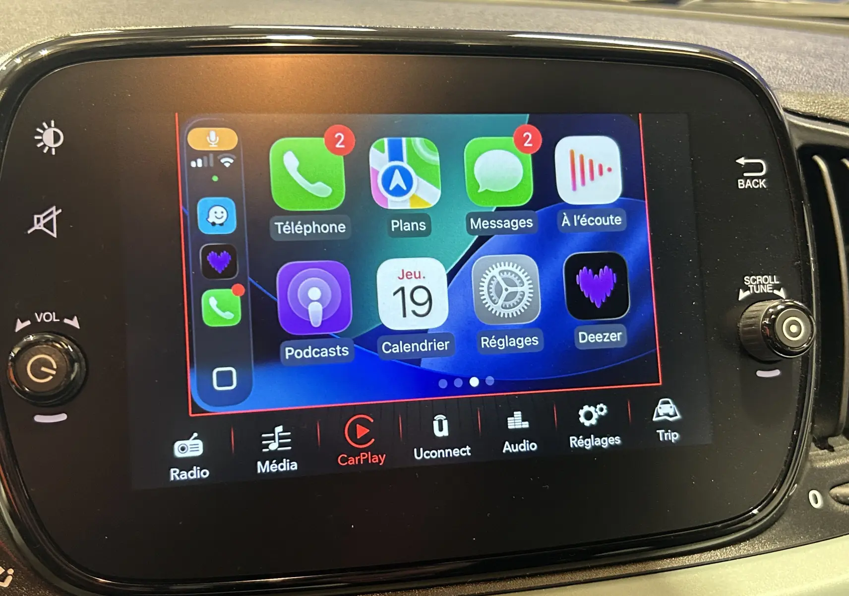 Écran tactile central de la Fiat 500 2023 affichant l'interface Apple CarPlay avec plusieurs applications visibles.