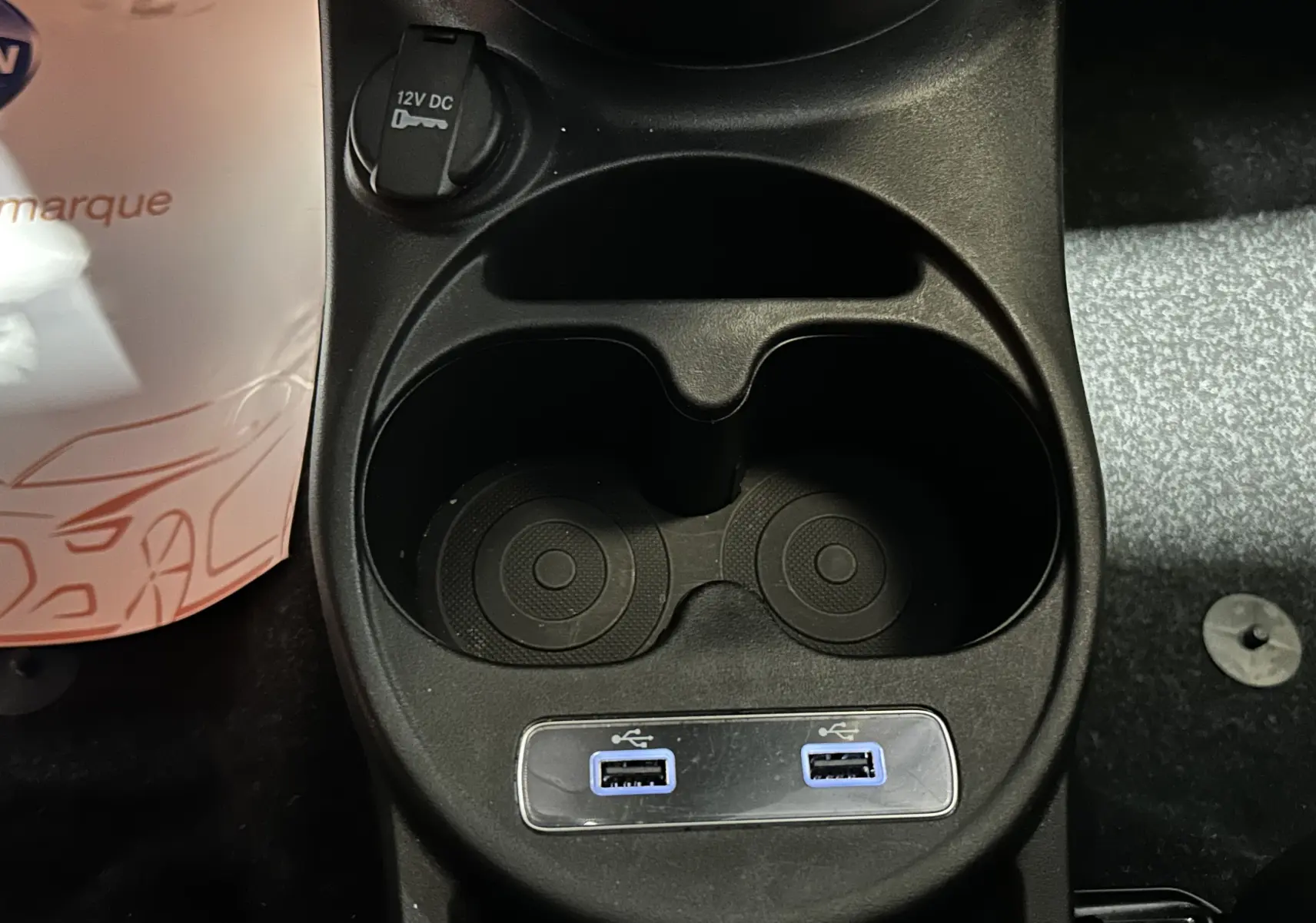 Gros plan sur la console centrale de la Fiat 500 2023, montrant porte-gobelets et deux ports USB.