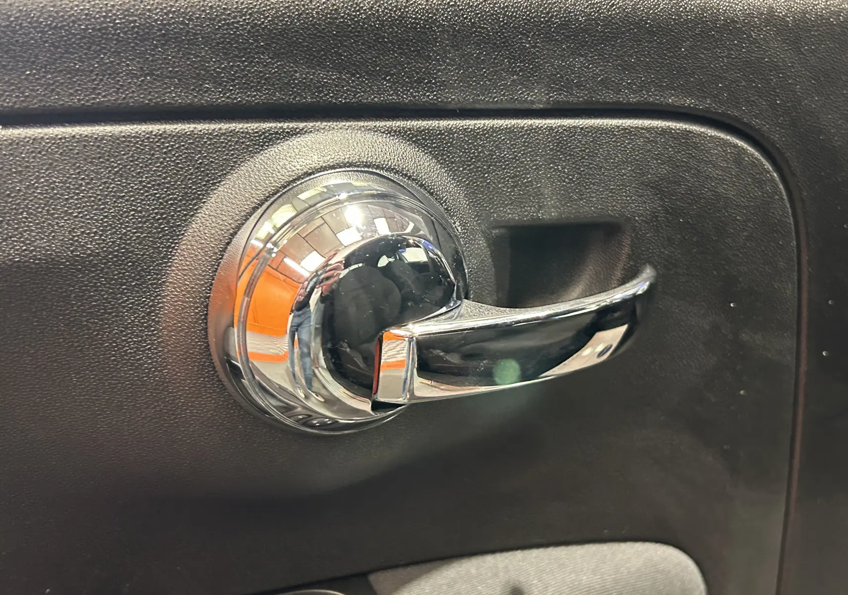 Poignée de porte intérieure chromée sur panneau noir de la FIAT 500 70 Hybride Pack Confort & Style 2023 en vert Rugiada.