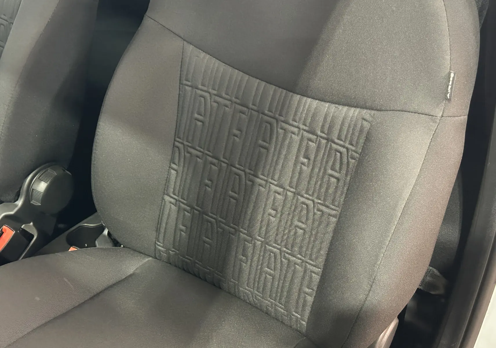 Gros plan sur le siège avant droit noir de la Fiat 500 2023 avec motif FIAT embossé au centre du dossier.