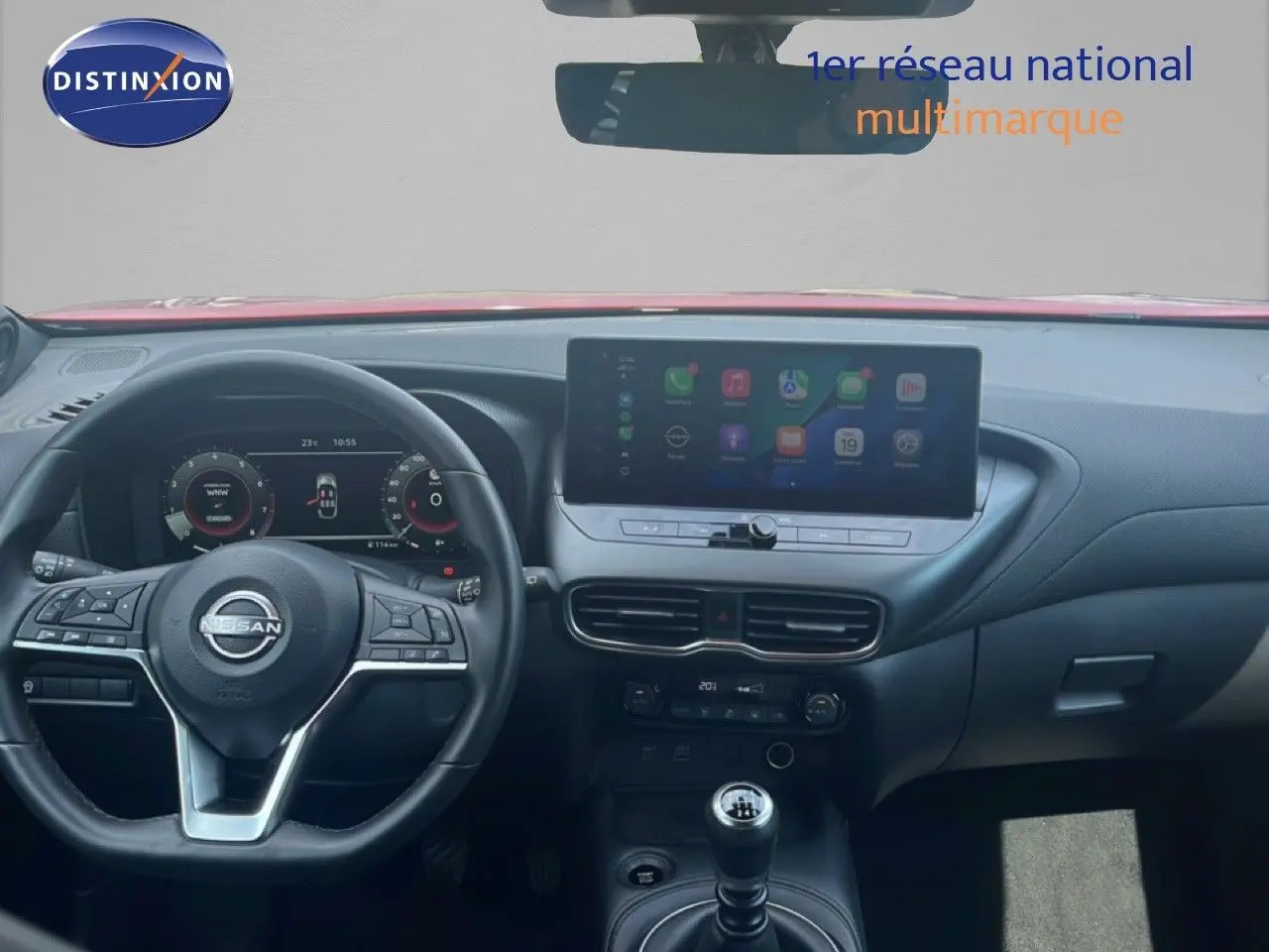 Vue intérieure du tableau de bord du Nissan Juke rouge Fuji Metal 2024, avec volant multifonction et écran tactile central.