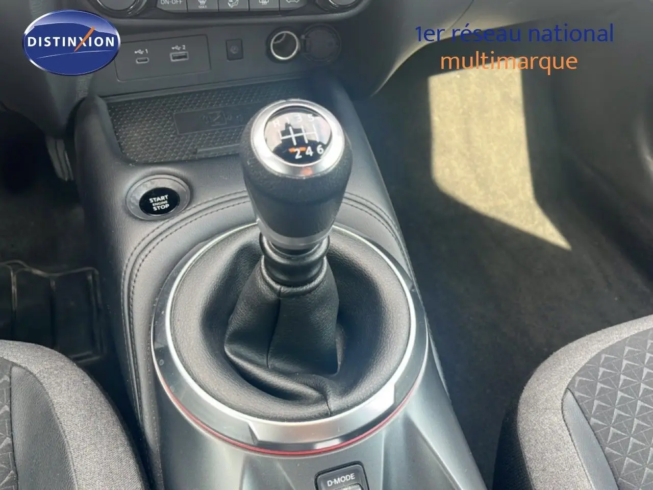 Le levier de vitesse manuel en gros plan au centre de l’habitacle noir du Nissan Juke rouge Fuji Metal 2024.
