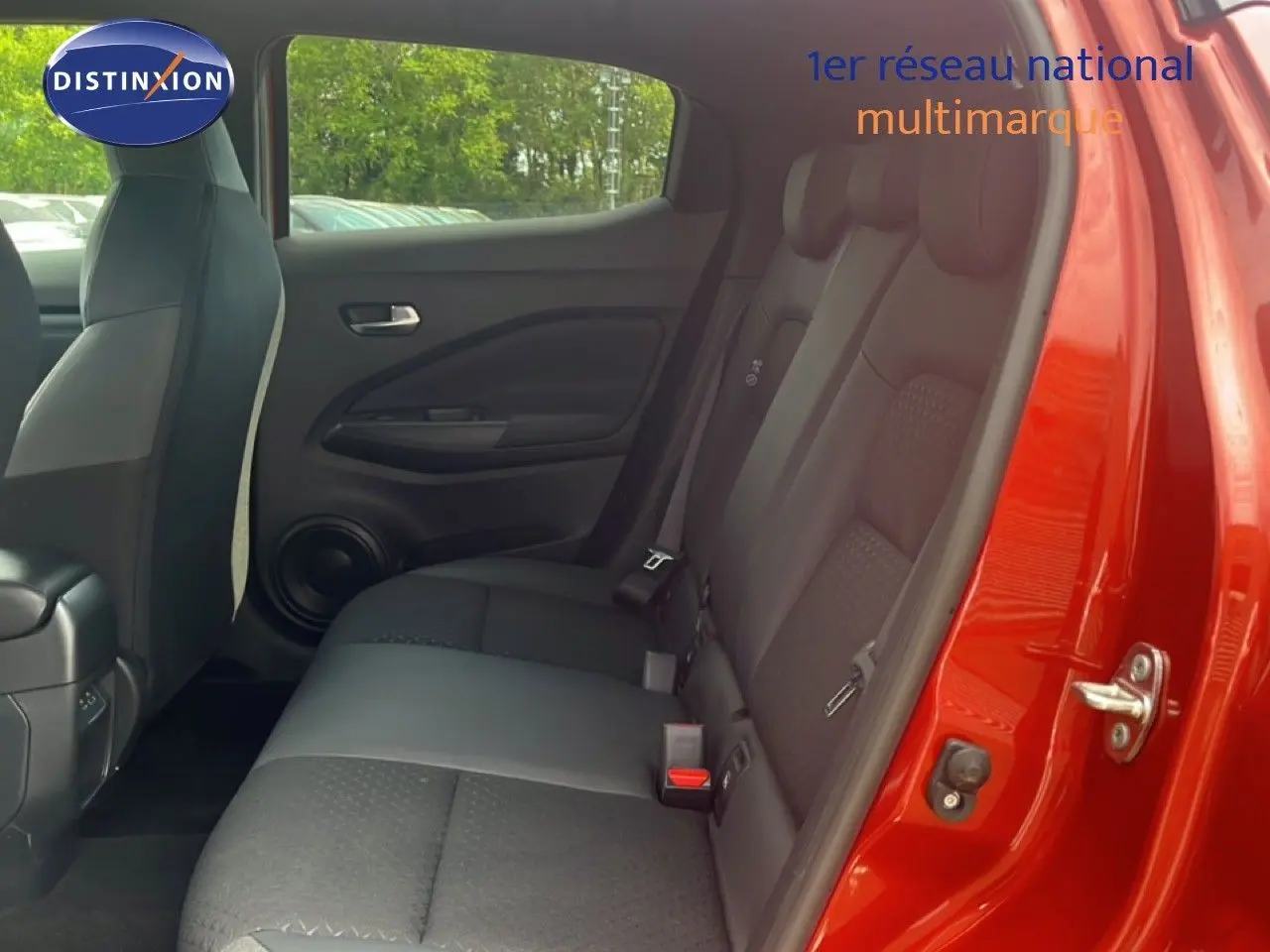 Vue intérieure côté droit des sièges arrière noirs du Nissan Juke rouge Fuji Metal 2024 avec porte ouverte.