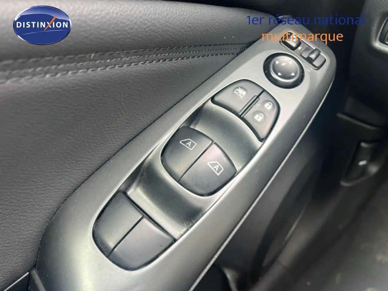 Gros plan sur les commandes des vitres électriques et rétroviseurs sur la porte intérieure noire d'un Nissan Juke 2024.