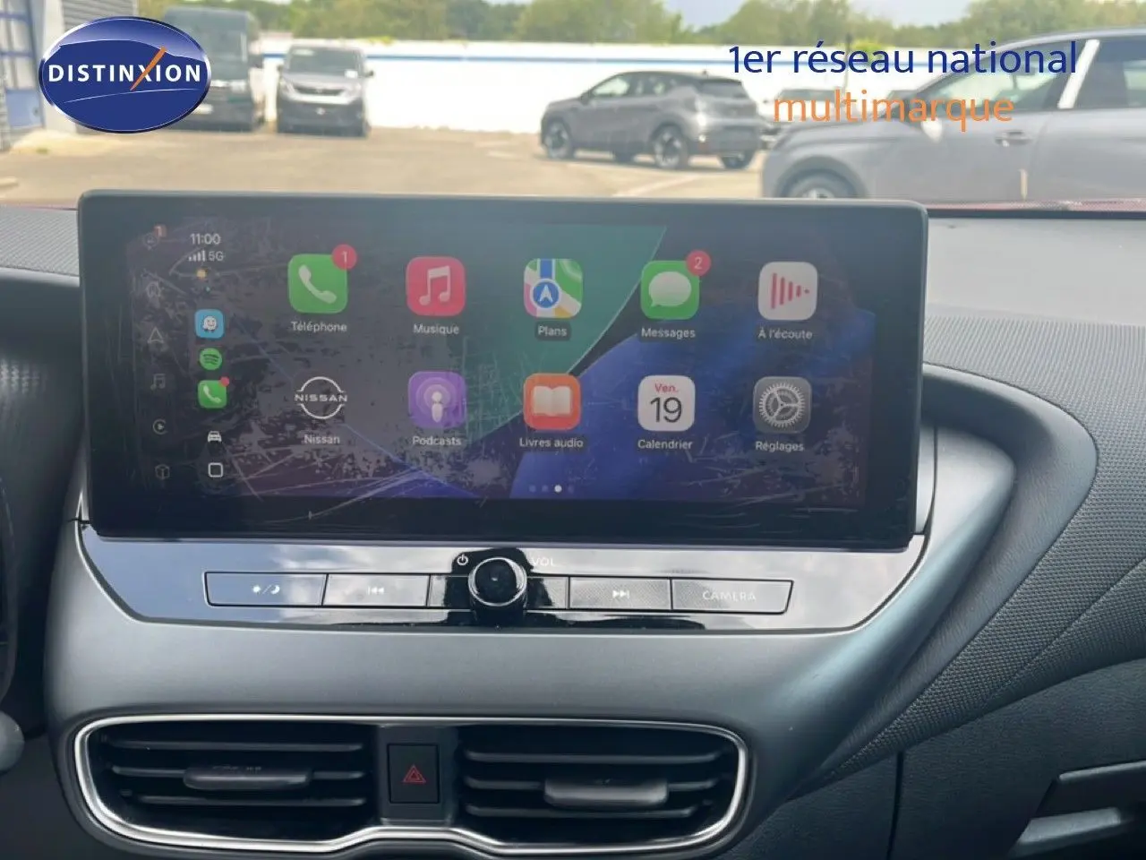 Écran tactile central du Nissan Juke 2024 affichant des applications, avec tableau de bord noir et aérateurs en vue frontale.