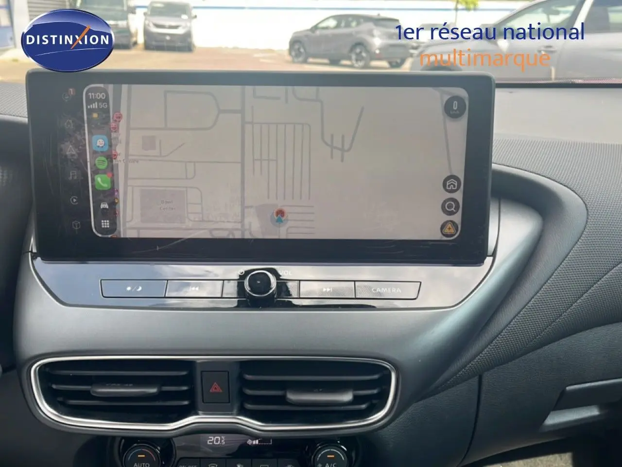 Vue rapprochée de l’écran tactile et de la console centrale du Nissan Juke rouge Fuji Metal 2024, avec commandes climatisation et navigation.