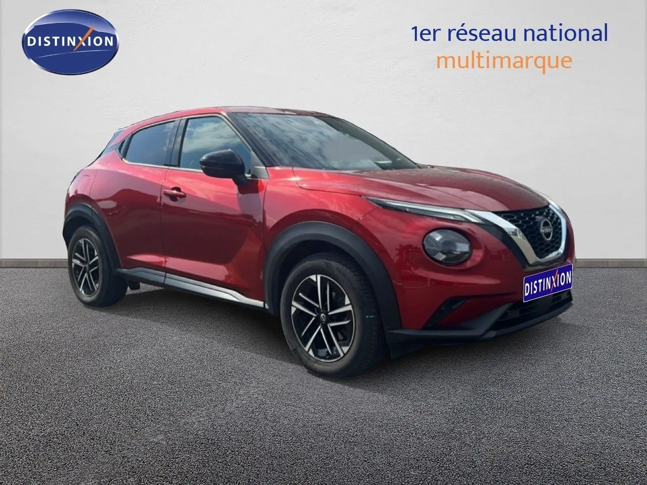 Nissan Juke rouge Fuji Metal en 3/4 avant droit, avec jantes noires et détails chromés visibles.