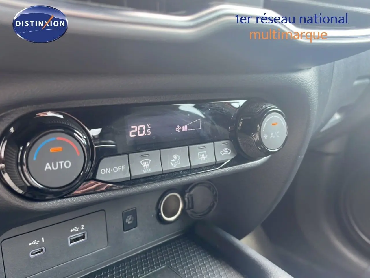 Détail de la console centrale du Nissan Juke 2024 rouge Fuji Metal, montrant les commandes de climatisation et ports USB.