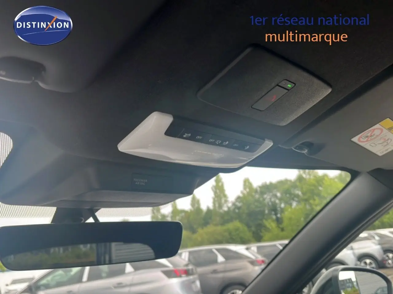 Vue intérieure du toit et rétroviseur d’un Nissan Juke rouge Fuji Metal 2024, avec commandes au plafond visibles.