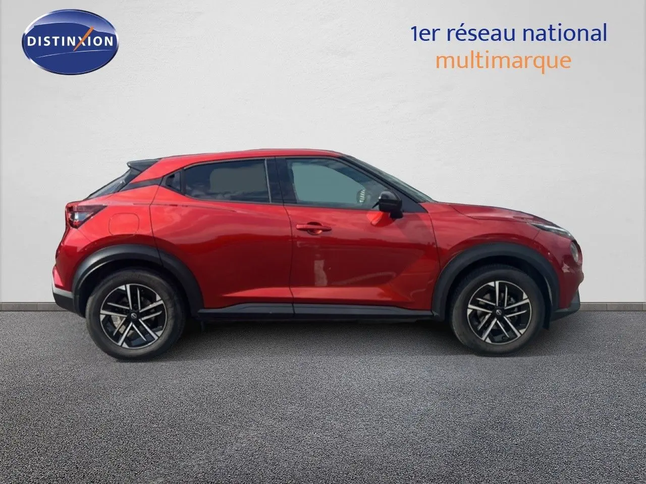 Vue latérale droite d'un Nissan Juke 2024 rouge Fuji Metal avec jantes alliage noires et toit noir contrasté.