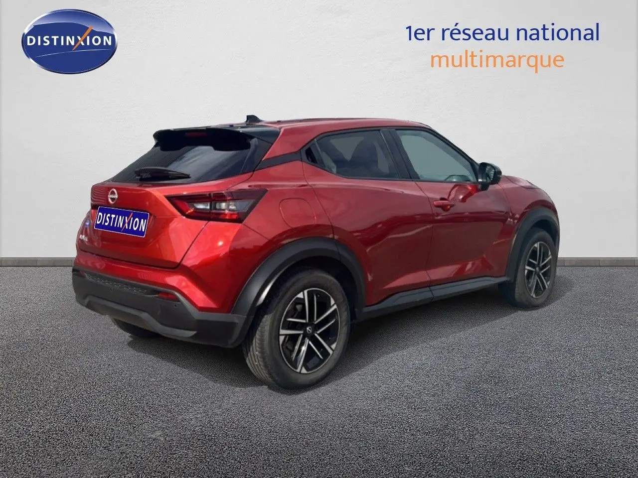Nissan Juke rouge Fuji Metal en 3/4 arrière droit, avec jantes noires et toit noir contrasté.