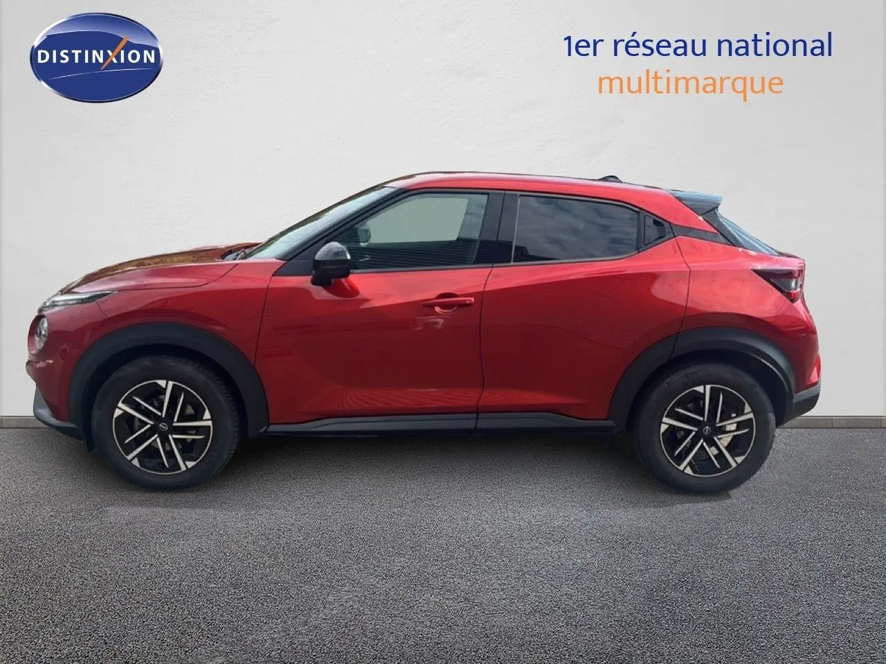 Profil droit du Nissan Juke 2024 rouge Fuji Metal avec jantes alliage et toit noir contrasté.
