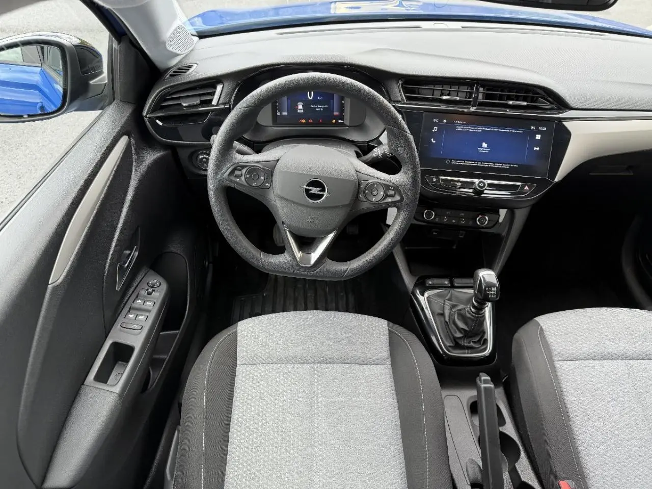 Vue intérieure centrée sur le volant Opel Corsa 2025, avec tableau de bord numérique et levier de vitesses manuel.