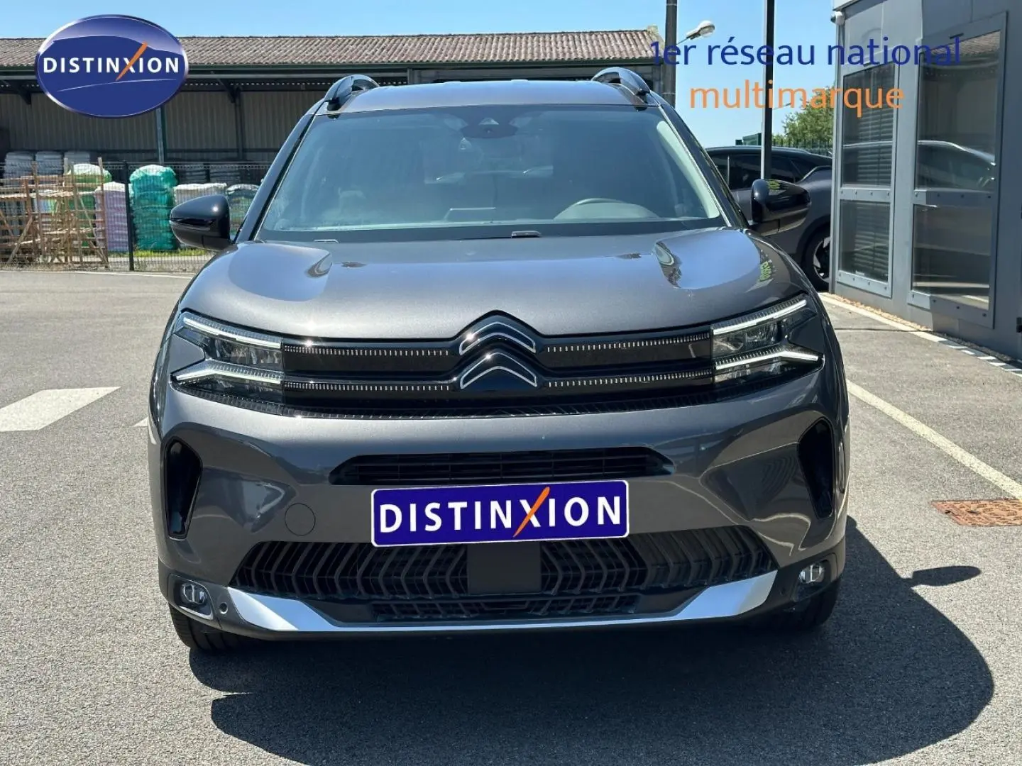 Vue avant d'un Citroën C5 Aircross gris Platinium avec calandre distinctive et barres de toit visibles.