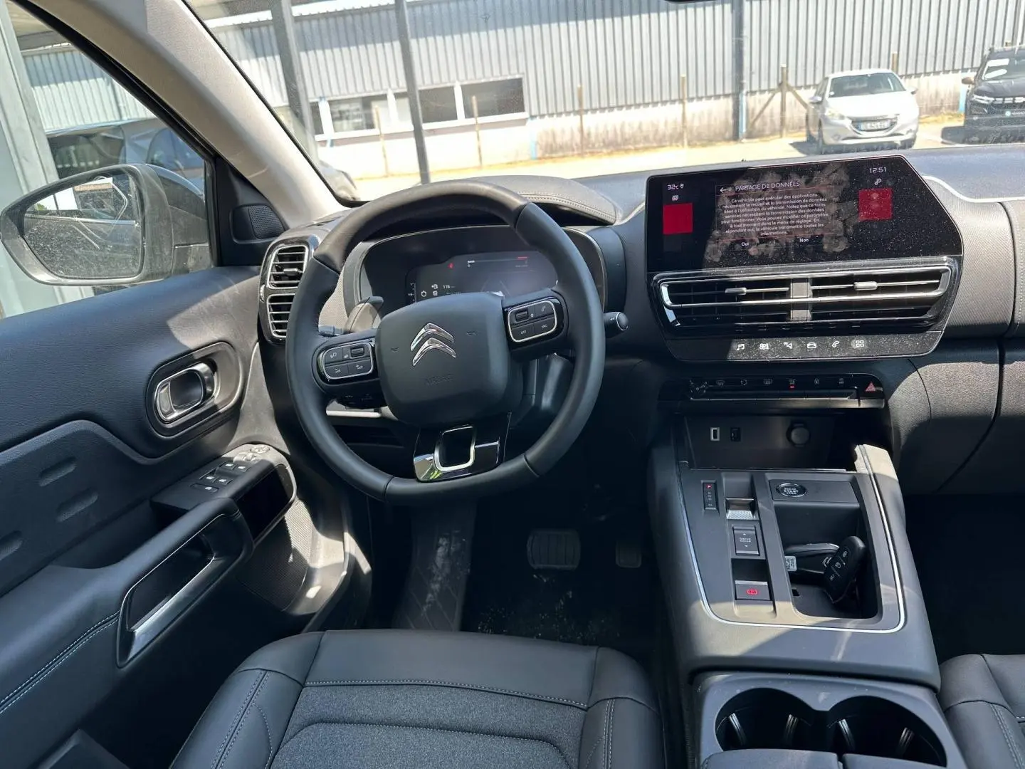 Vue intérieure du poste de conduite du Citroën C5 Aircross 2025, volant cuir noir et écran tactile central.