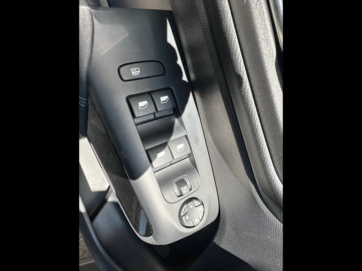 Gros plan sur les commandes des vitres et rétroviseurs côté conducteur du Citroën C5 Aircross 2025, intérieur noir.