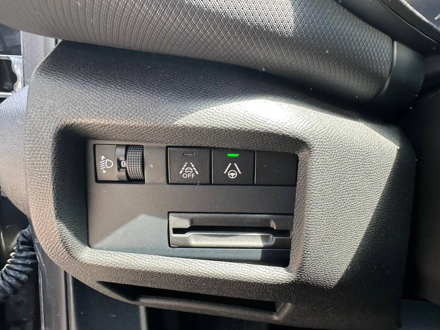 Gros plan sur les commandes d'assistance et réglage des phares côté gauche du tableau de bord du Citroën C5 Aircross gris Platinium.