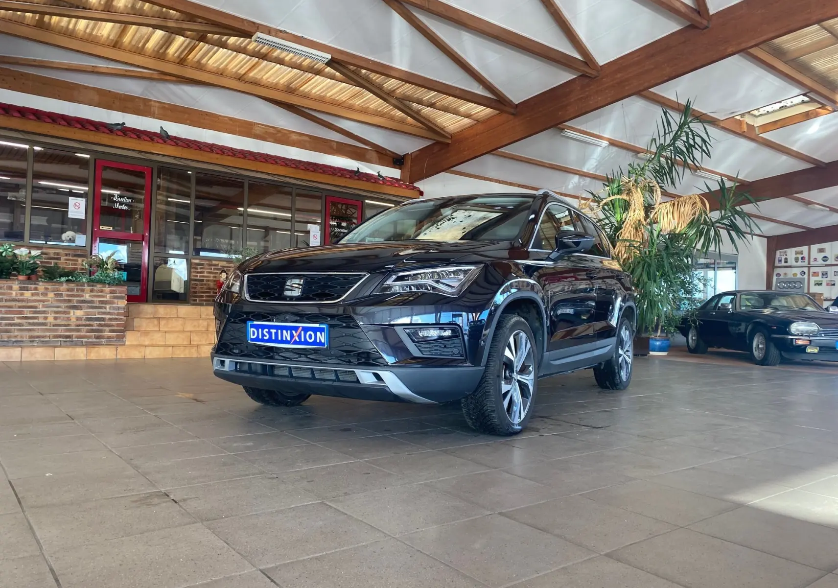 SEAT Ateca Urban noir vue 3/4 avant droit dans un showroom avec lumière naturelle et décor intérieur.