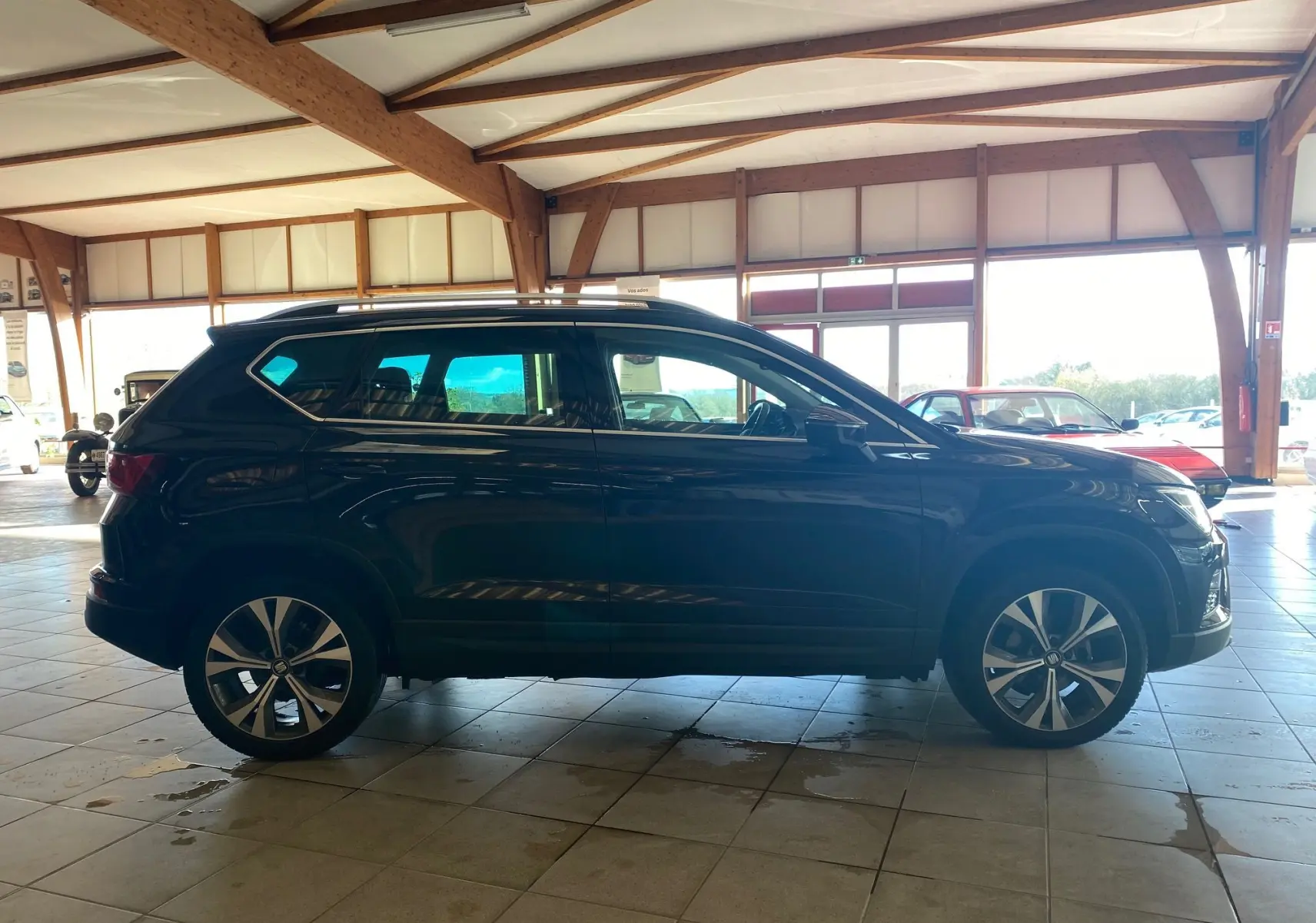 Profil côté gauche d'un SUV SEAT Ateca Urban noir 2019 avec jantes alliage et toit ouvrant en intérieur lumineux.