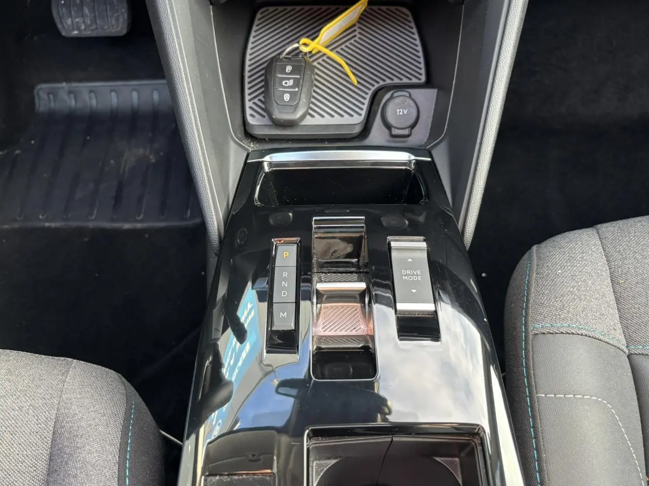 Vue plongeante sur la console centrale noire brillante de la Citroën C4 2024 avec levier de vitesses et bouton Drive Mode.