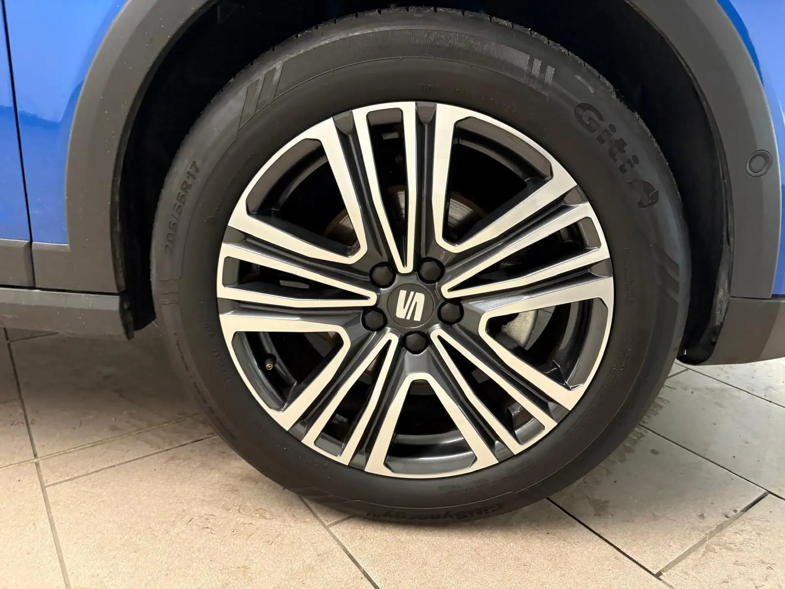 Gros plan sur la roue avant droite du SEAT Arona bleu saphir avec jante alliage bicolore et logo central.