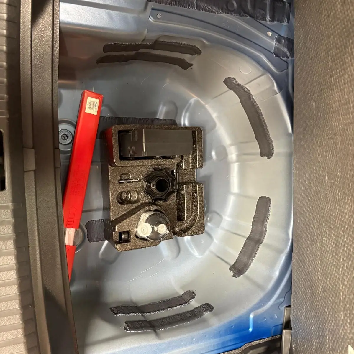 Vue rapprochée de la zone de rangement sous le coffre d’un SEAT Arona bleu saphir, montrant l’emplacement pour roue de secours.