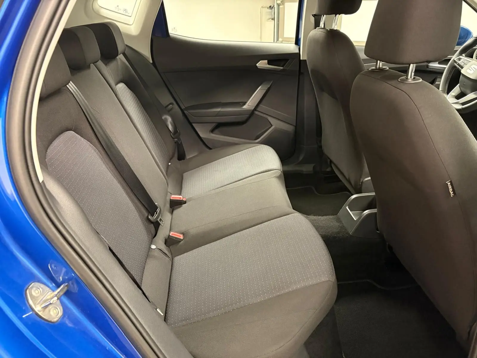 Vue intérieure côté gauche des sièges arrière gris d’un SEAT Arona 2025 bleu saphir avec porte ouverte.