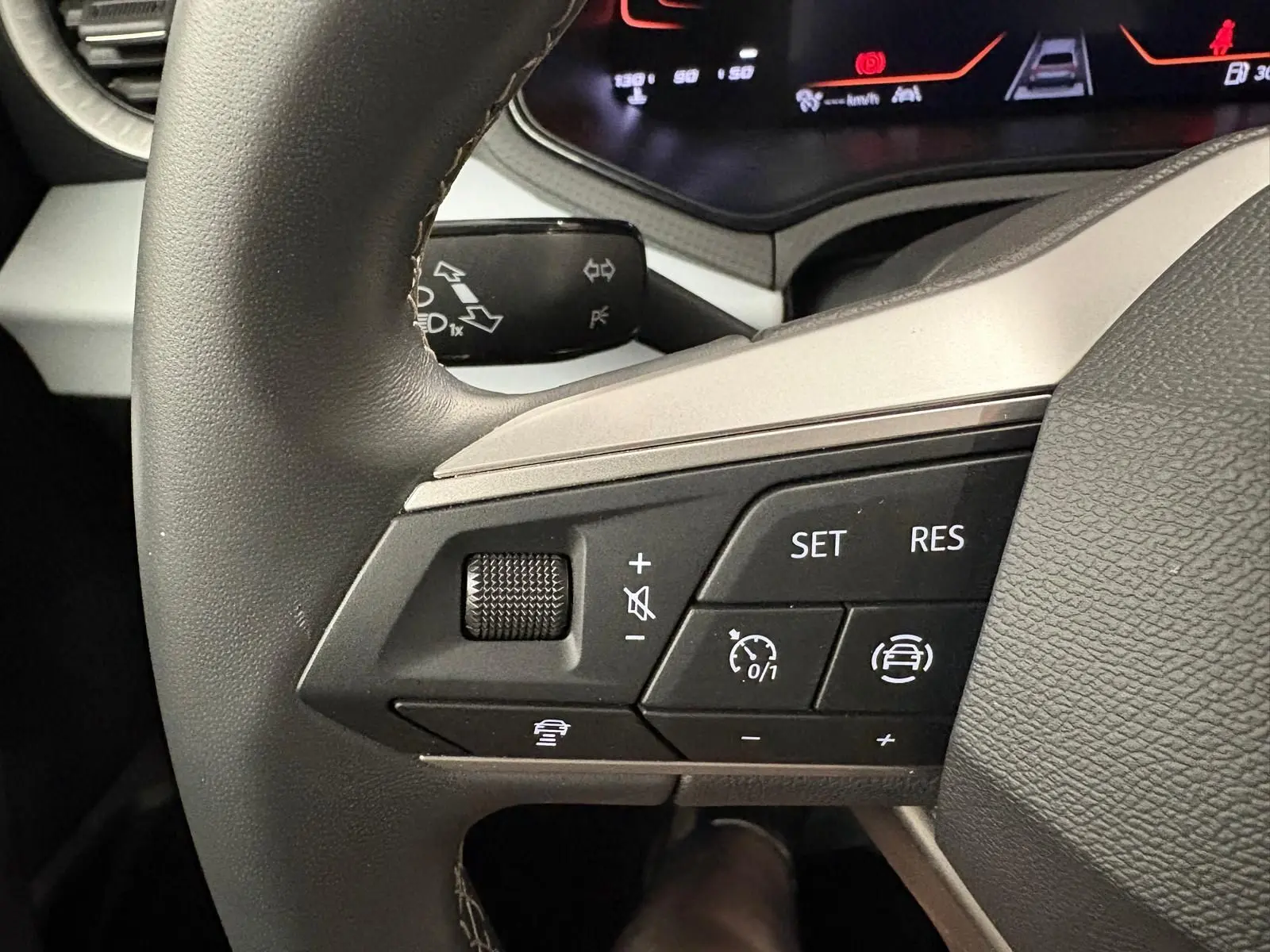 Gros plan sur les commandes au volant à gauche du SEAT Arona 2025, soulignant les fonctions régulateur adaptatif et assistance conduite.