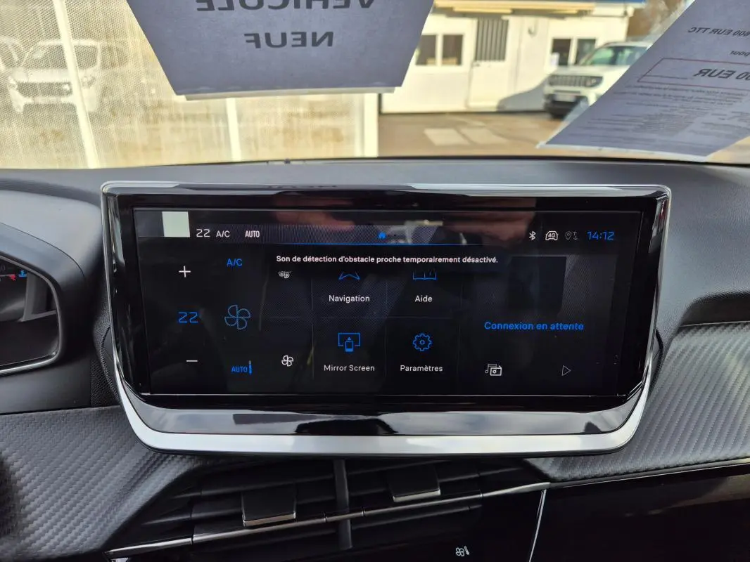 Écran tactile central du tableau de bord de la Peugeot 208 blanc, affichant les options de navigation et climatisation.