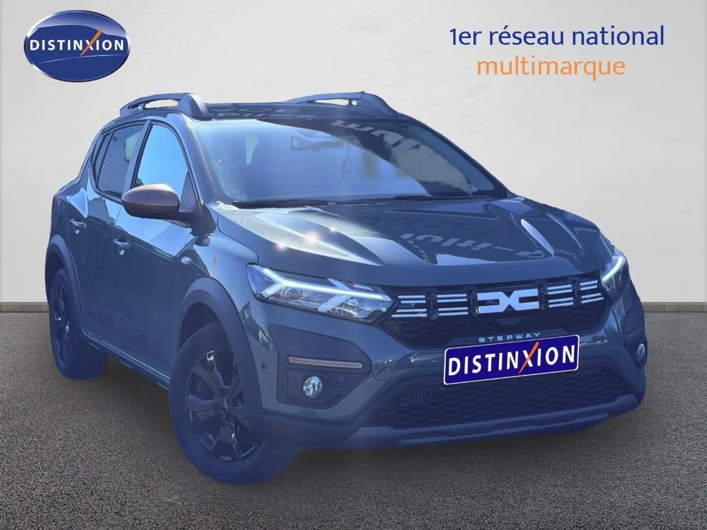 Vue 3/4 avant droite d'une Dacia Sandero Stepway 2025 en kaki lichen avec jantes noires et barres de toit.