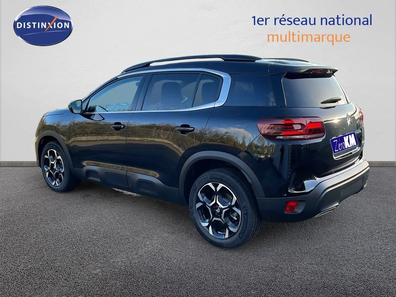 Vue 3/4 arrière droite d'un Citroën C5 Aircross noir Perla Metal avec jantes bi-ton et barres de toit visibles.