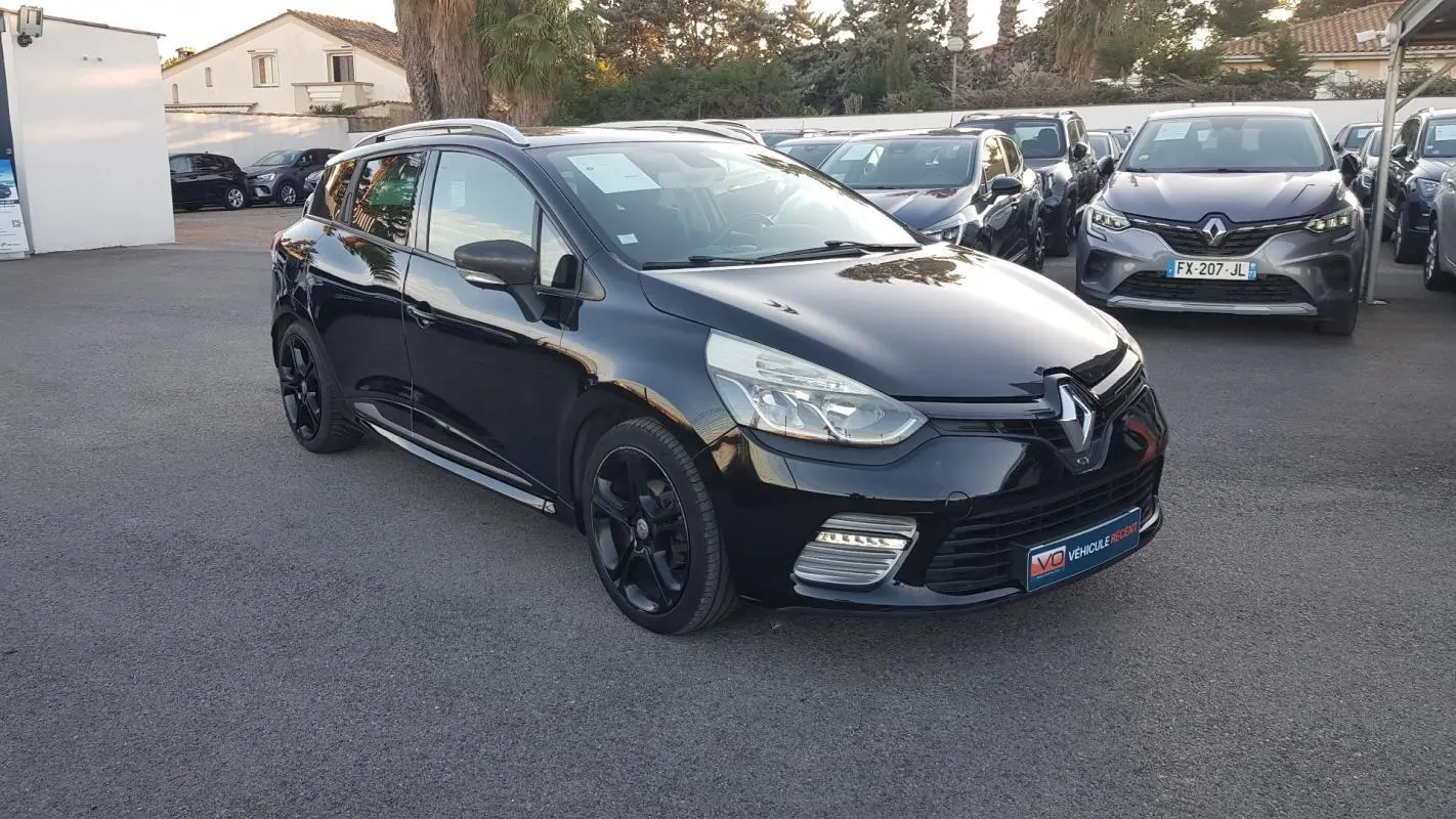 Renault Clio IV Estate noir en 3/4 avant droit, avec jantes alliage noires et feux diurnes LED visibles.