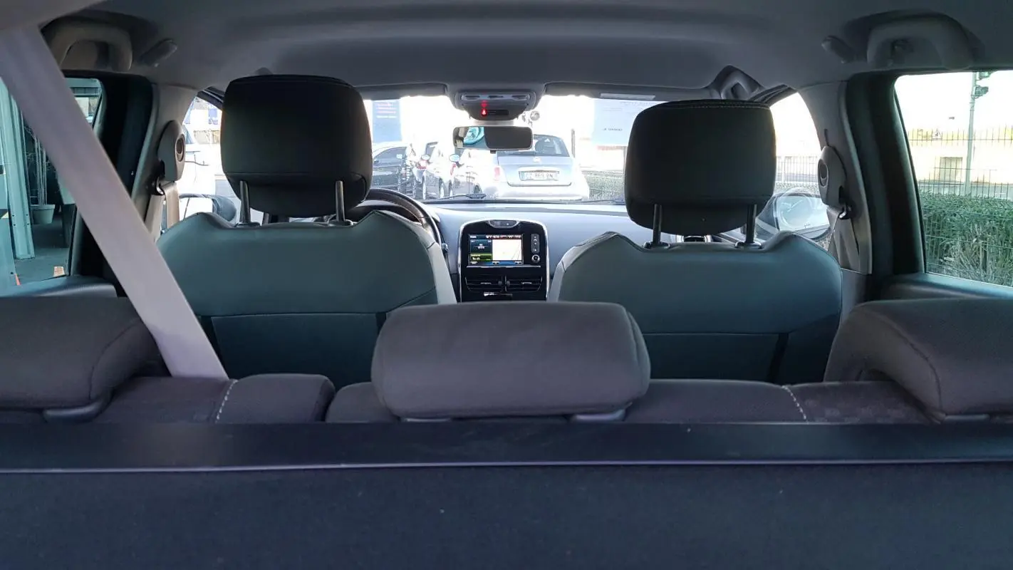 Vue intérieure arrière de la Renault Clio IV Estate noire, montrant les sièges avant et l'écran central du tableau de bord.