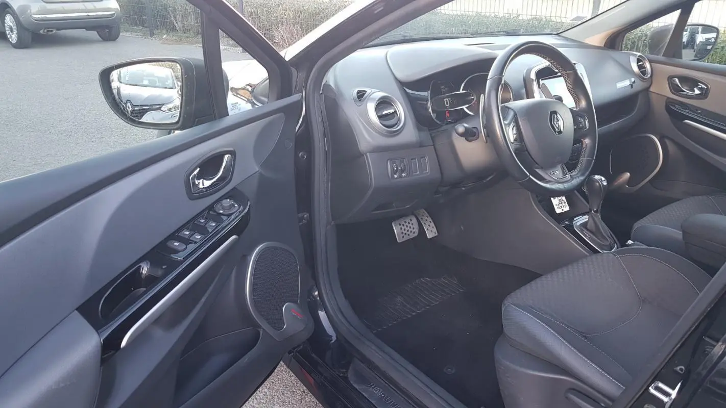 Intérieur côté conducteur d'une Renault Clio IV Estate noir, volant cuir et console avec boîte automatique visible.