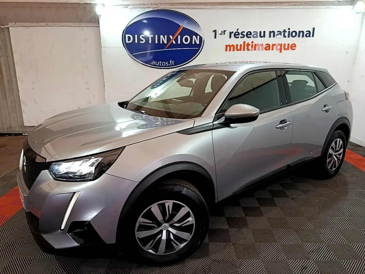 Peugeot 2008 gris clair vue 3/4 avant droit dans un showroom avec phares LED et jantes alliage.