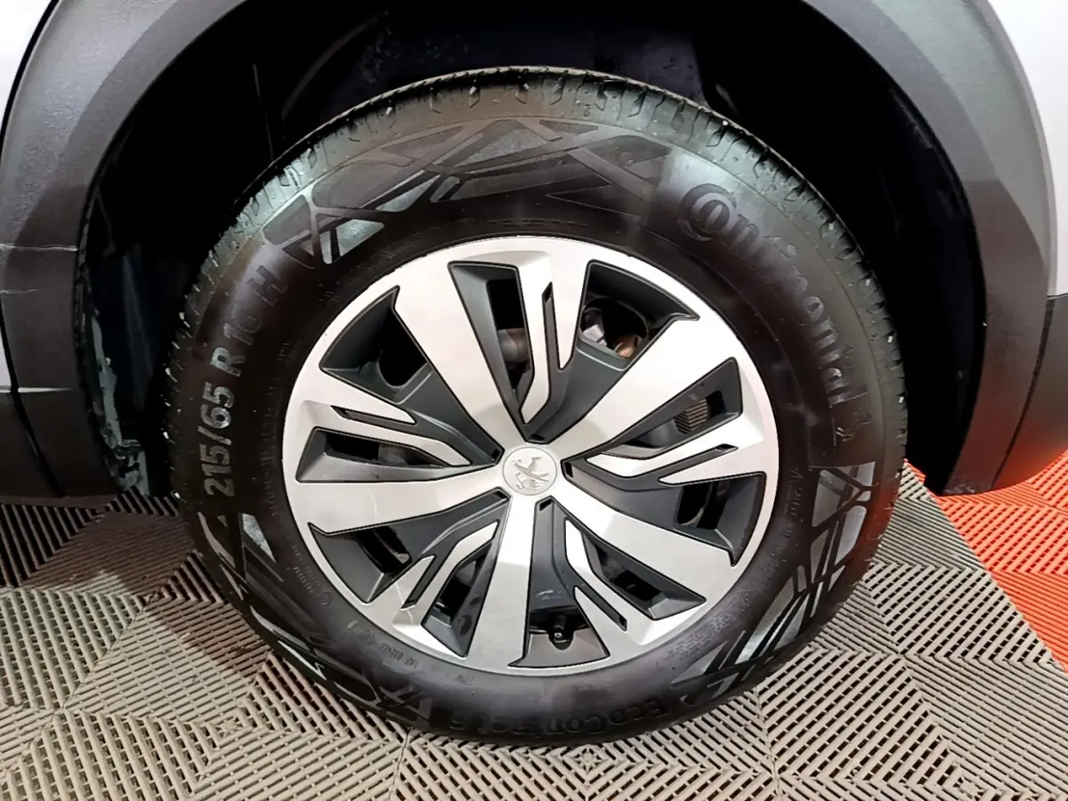 Gros plan sur la roue avant droite d’un Peugeot 2008 gris clair, avec jante alliage au design moderne.