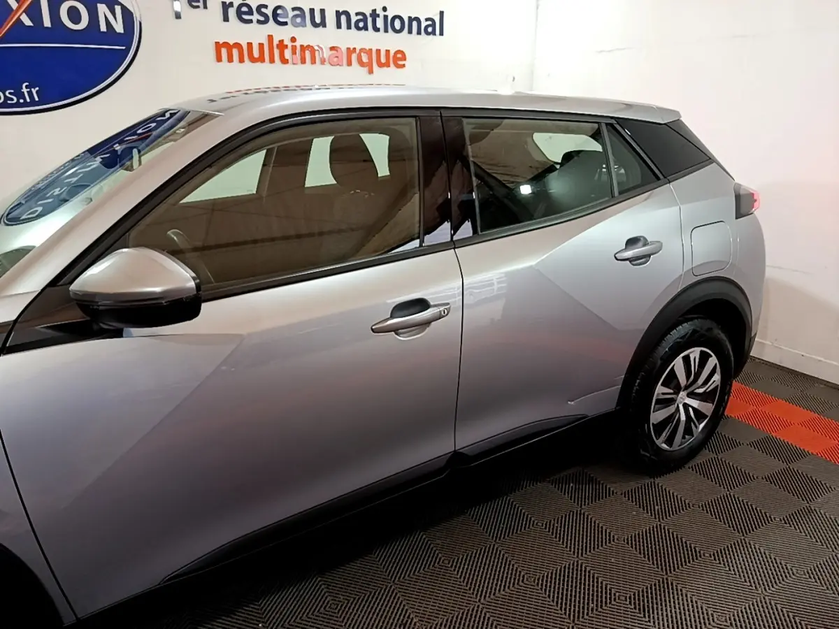 Vue latérale droite d'un Peugeot 2008 gris clair, mettant en valeur les lignes anguleuses et les jantes modernes.