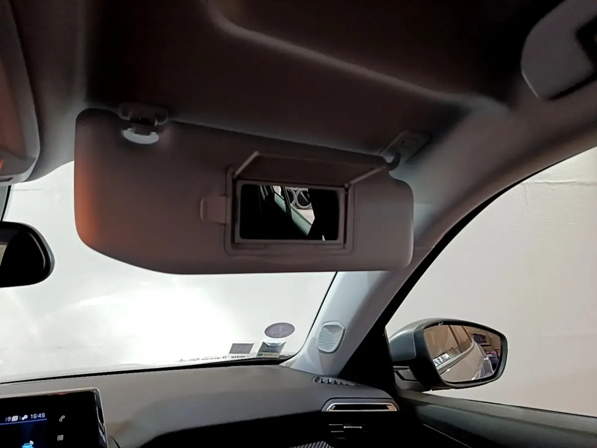 Vue intérieure côté conducteur du Peugeot 2008 gris clair 2021, avec pare-soleil déplié et rétroviseur latéral visible.