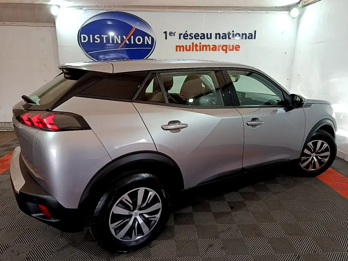 Vue 3/4 arrière droite d’un Peugeot 2008 gris clair avec feux arrière LED et jantes alliage dans un showroom.
