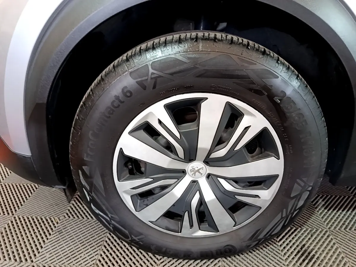 Gros plan sur la roue avant droite d’un Peugeot 2008 gris clair, avec jante en alliage au design moderne.