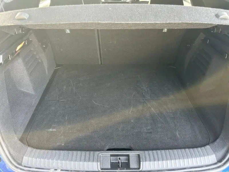 Coffre ouvert vu de l'arrière d'une Renault SYMBIOZ rouge Flamme, espace de chargement vide et tapis noir.