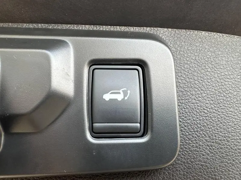 Bouton intérieur noir avec symbole d'ouverture du hayon, détail de la Renault SYMBIOZ rouge Flamme 2025.