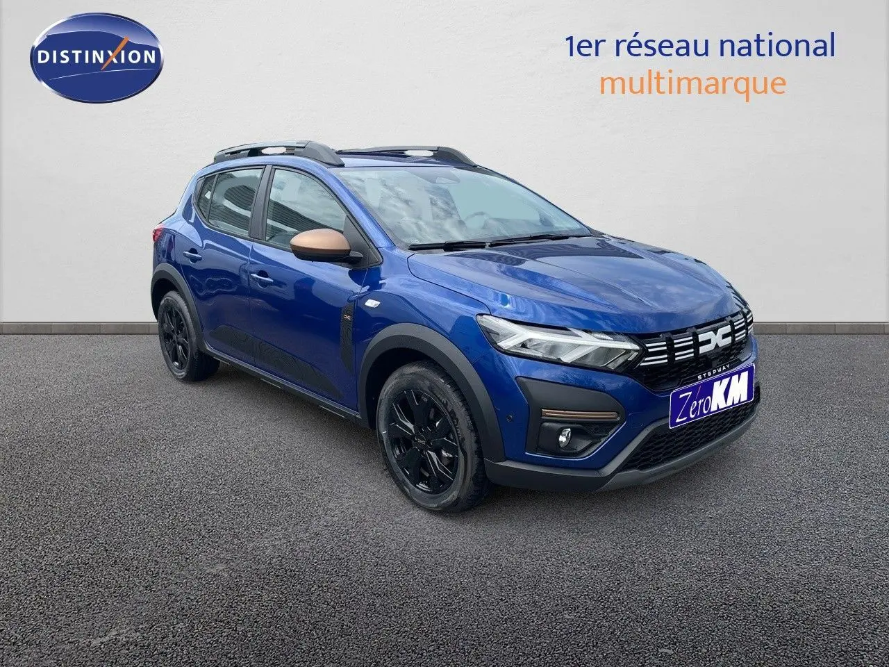 Vue 3/4 avant d'une Dacia Sandero Stepway 2024 bleu Iron Metal avec jantes noires et rétroviseurs bronze.