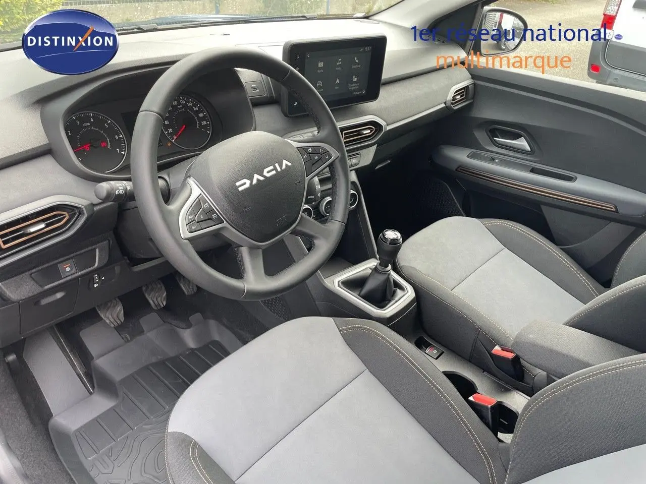 Vue intérieure côté conducteur de la Dacia Sandero Stepway 2024, avec volant multifonction et sellerie gris clair.