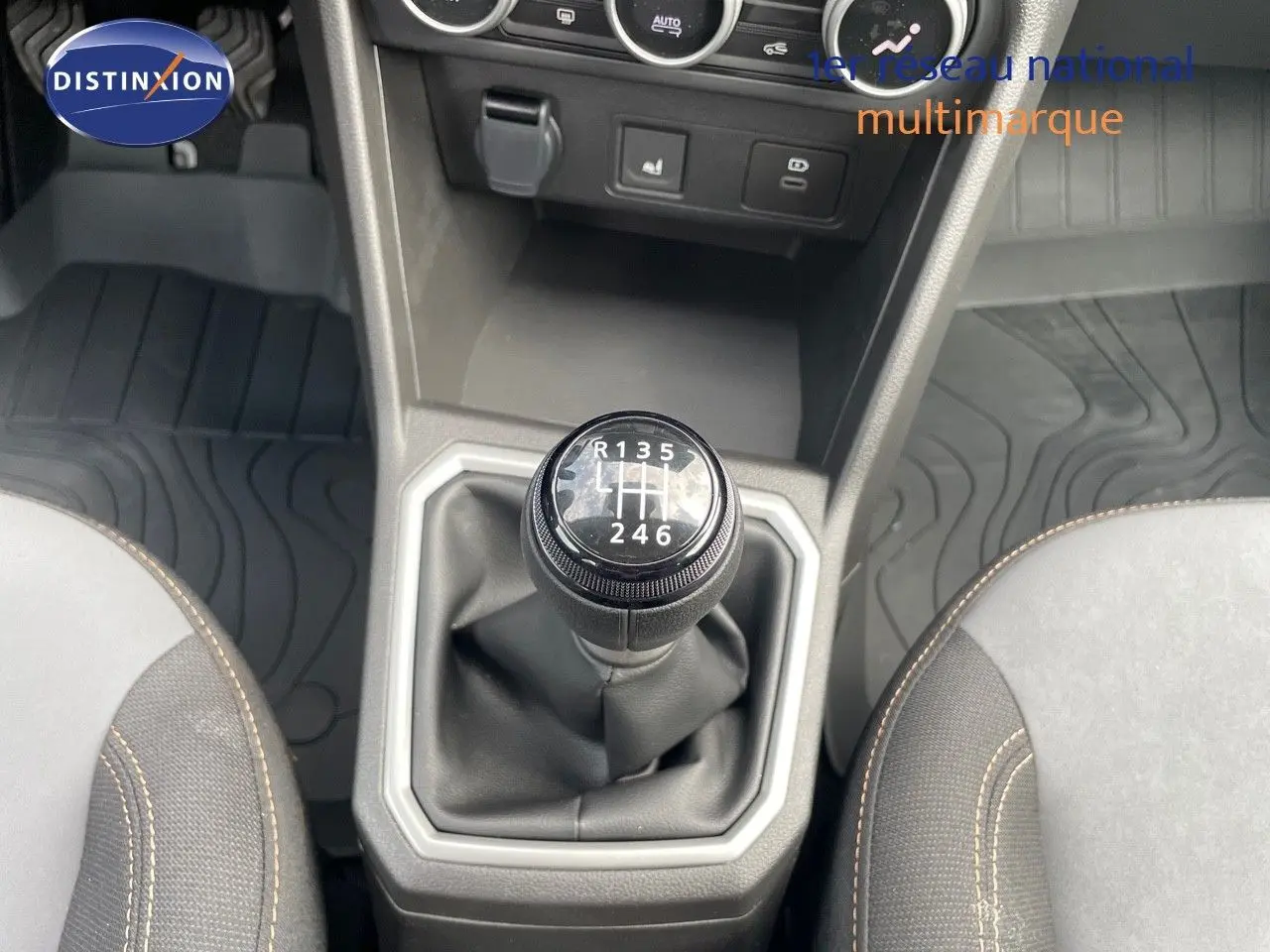 Le levier de vitesses manuel de la DACIA SANDERO STEPWAY 2024, entouré de sièges gris et noir avec surpiqûres beige.