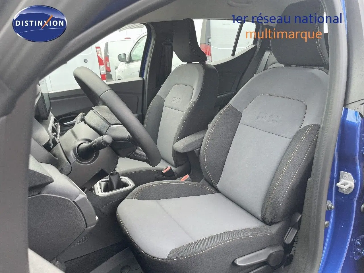 Vue intérieure côté conducteur de la Dacia Sandero Stepway 2024 bleu Iron Metal, sièges gris avec surpiqûres contrastées.