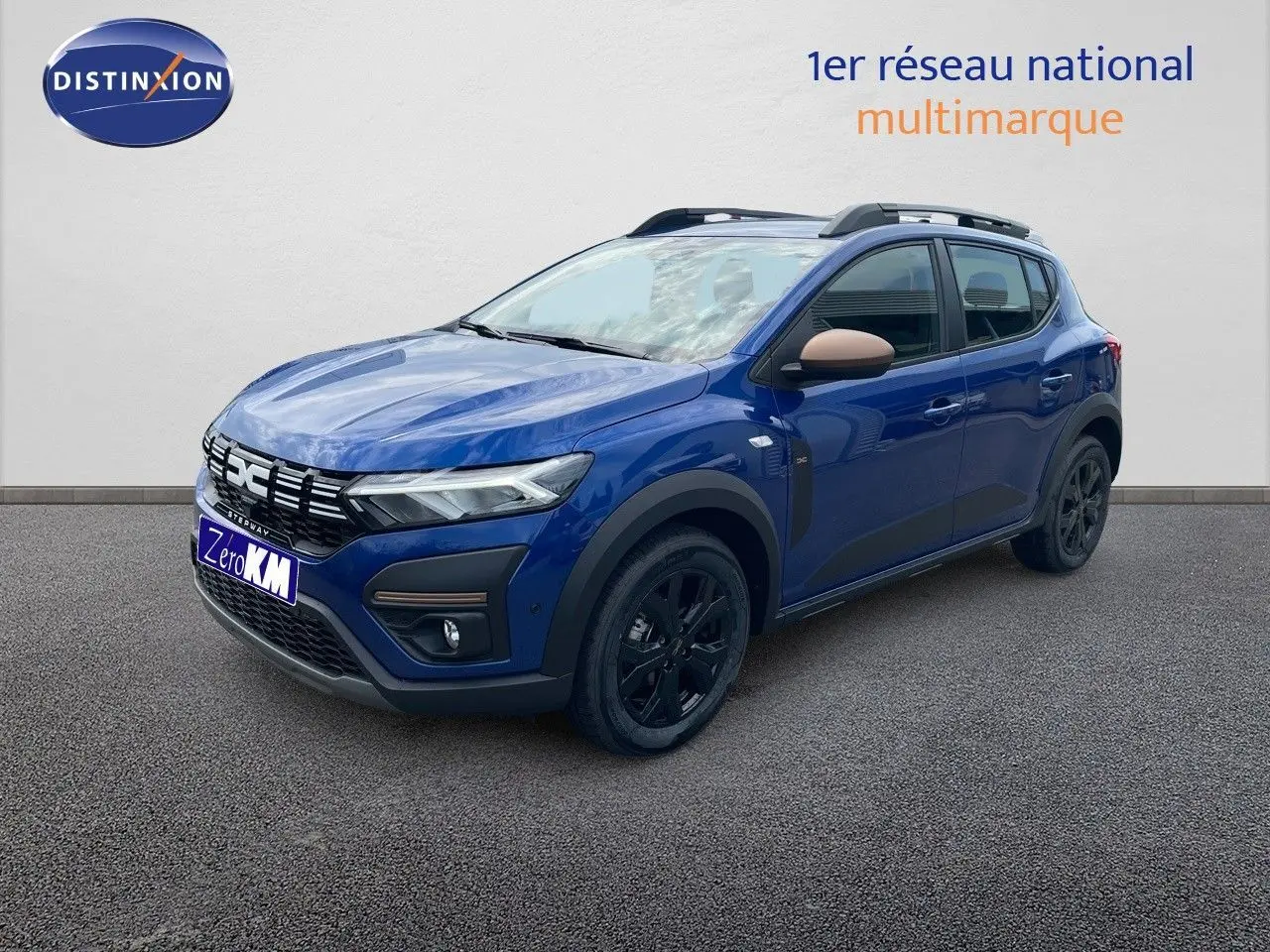 Vue 3/4 avant droite d'une Dacia Sandero Stepway 2024 bleu iron metal avec jantes noires et coques de rétroviseur beige.