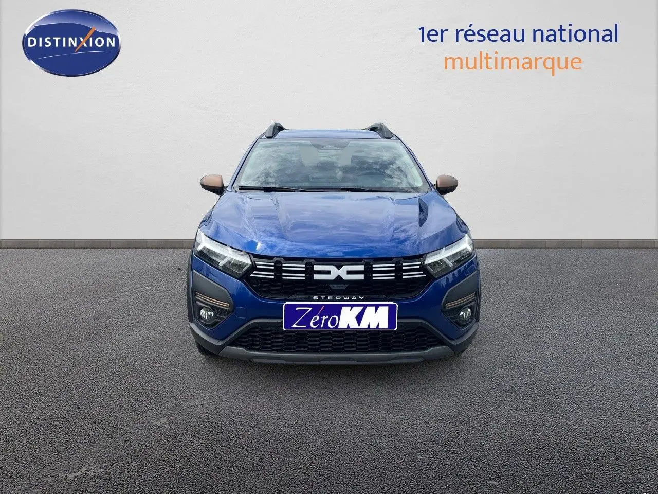 Vue frontale d'une Dacia Sandero Stepway 2024 en bleu Iron Metal avec calandre noire et phares LED allumés.