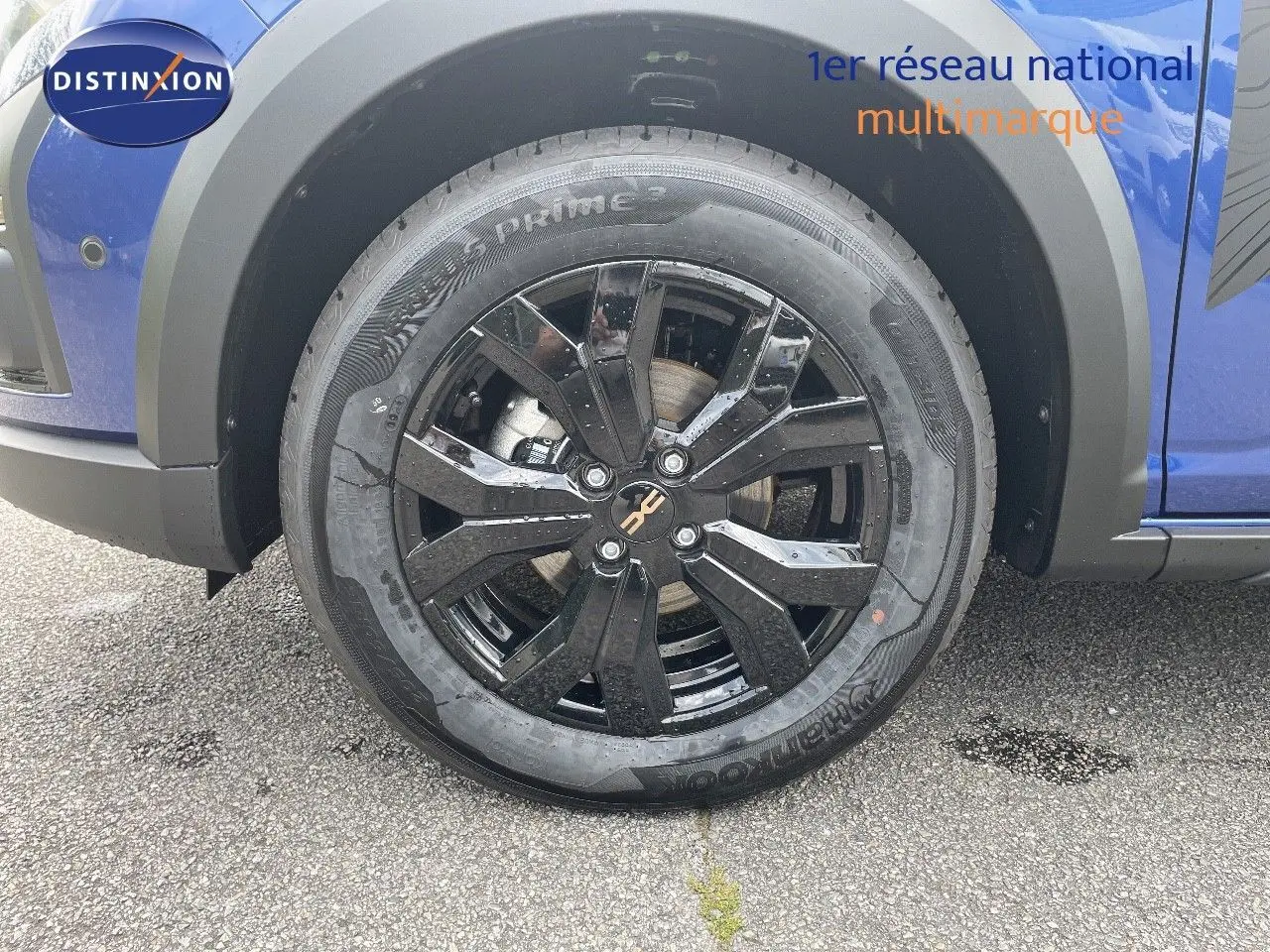 Gros plan sur la roue avant gauche noire brillante du Dacia Sandero Stepway bleu Iron Metal 2024.